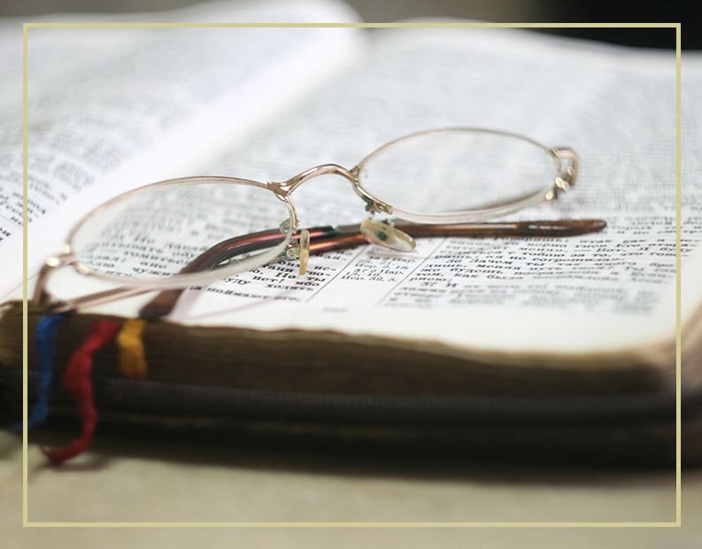 A pair of glasses sitting on top of an open book.