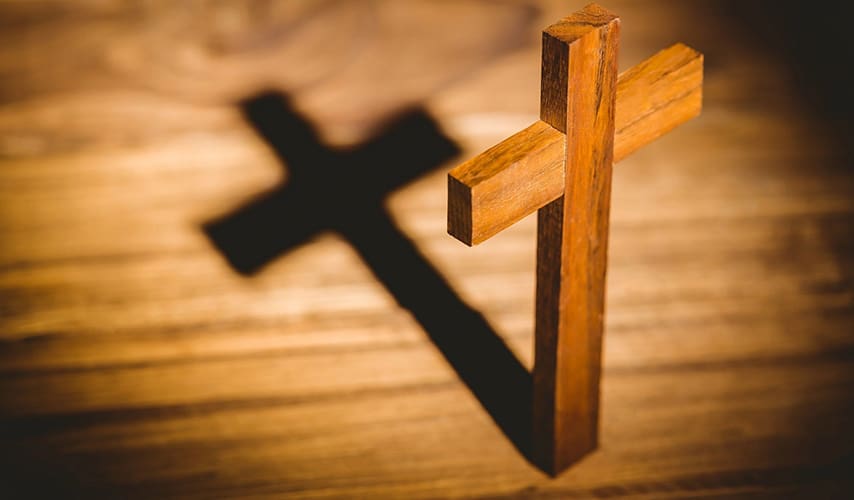 A wooden cross casting a shadow on the ground.