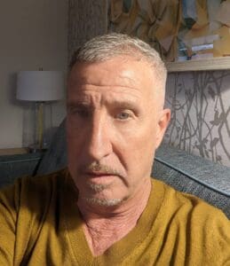 A man with gray hair and a yellow shirt.