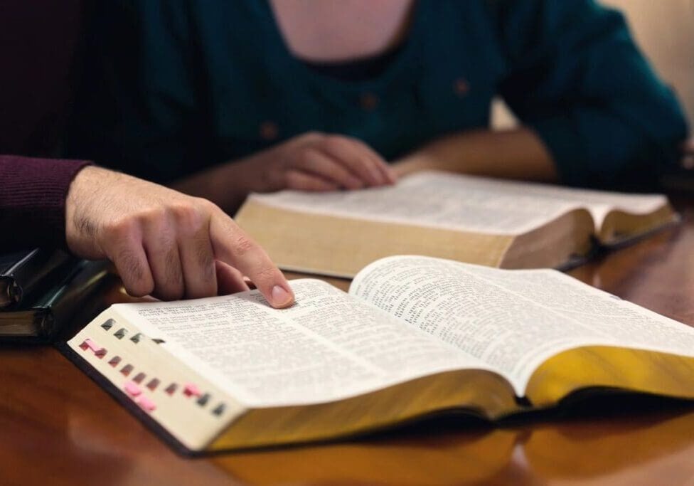 A person is reading the bible on their desk.